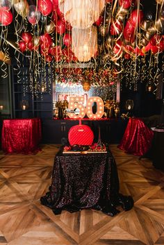 the table is decorated with red, gold and black balloons that spell out boo on it