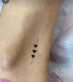 small black hearts tattoo on the side of a woman's leg, with dots in it