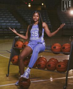 a female basketball player sitting on a bench with her arms out in front of the camera