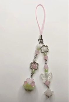 a pink and green beaded keychain hanging from a hook on a white surface