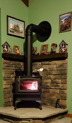 a wood burning stove sitting inside of a living room next to a fire place with pictures on the wall