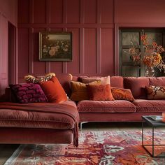 a living room with red walls and furniture in the corner, including a large sectional couch