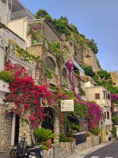 a scooter parked in front of a building with flowers growing on the side