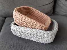 two crocheted baskets sitting on top of a gray couch next to each other