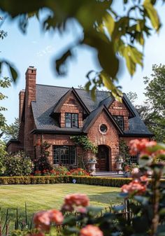 a large brick house surrounded by flowers and greenery