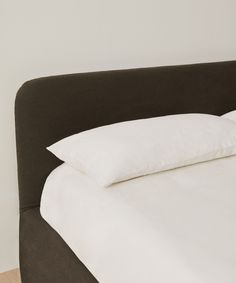 a bed with white sheets and pillows on it