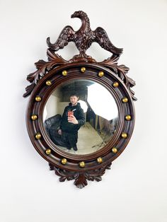 a mirror hanging on the wall with a reflection of a person in it and an eagle