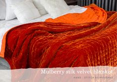 an orange blanket sitting on top of a bed