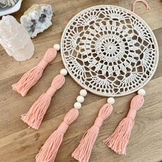 a white doily with tassels and other accessories on a wooden table top