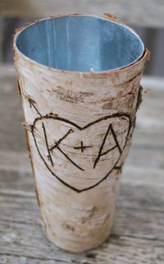 a cup that has been carved into the side of a tree trunk with hearts drawn on it