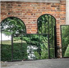 three mirrors on the side of a brick building with trees reflected in them and one is leaning against a wall