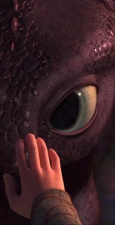 a close up of a person touching an alien creature's face with its eyes