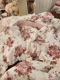 an unmade bed with pink flowers on it