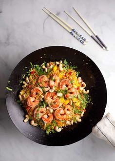 shrimp and vegetable stir fry in a wok with chopsticks on the side