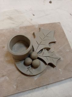 an object made out of clay sitting on top of a cutting board next to a leaf