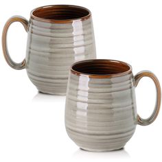 two coffee mugs sitting next to each other on a white surface with brown rim