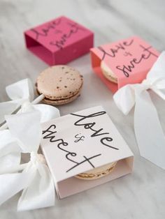 three small boxes with different types of cookies in them on a white tablecloth covered surface