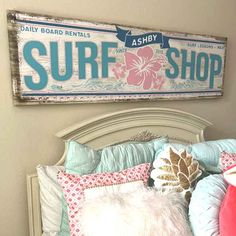 a surf shop sign above a bed with pillows