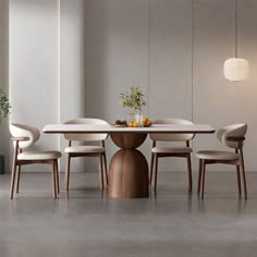 a dining table with four chairs around it and a vase on the table next to it