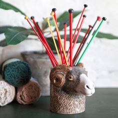 a ceramic animal head with red, yellow and green sticks sticking out of it's mouth