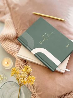 two notebooks sitting on top of each other next to a glass vase with flowers