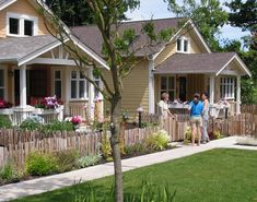 two people are walking in front of some small houses with flowers on the porchs