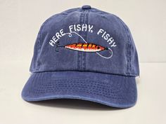 there is a blue hat that has a fish on it and the words here, fishy, fishy