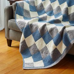 a blue and white blanket sitting on top of a couch next to a wooden chair