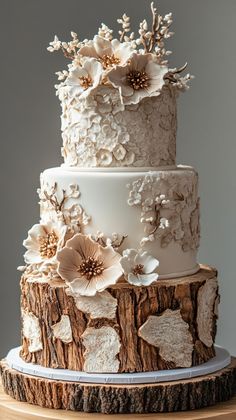 a three tiered cake decorated with flowers and leaves on top of a wooden table