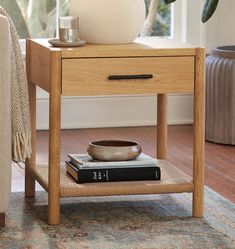 a wooden table with a book and vase on it next to a couch in a living room