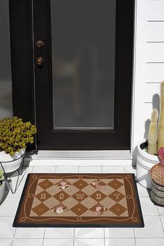 a door mat that is on the outside of a house with potted plants next to it