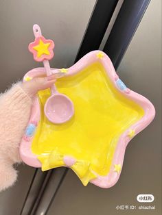 a pink and yellow star shaped toy with spoons in it's holder on the wall