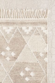 a beige and white rug with fringes on it