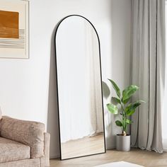 a large mirror sitting on top of a floor next to a chair and potted plant