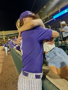 two people hugging each other at a baseball game