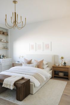 a large white bed sitting in a bedroom under a chandelier