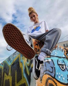 a woman sitting on top of a skateboard next to a wall covered in graffiti