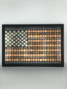 an american flag made out of coins is displayed on the wall in front of a gray background