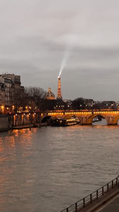 the eiffel tower is lit up at night over the river in paris, france