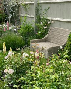 a garden filled with lots of flowers next to a wooden bench in the middle of it