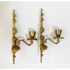 two brass candle holders are on the wall