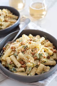 two bowls filled with pasta and vegetables on top of a table