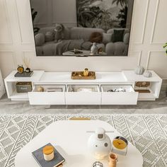 a living room with white furniture and a flat screen tv mounted on the wall above it