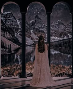 a woman standing in front of an arch looking out at the mountains and lake below