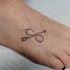 a small tattoo on the foot of a person with an arrow and two hearts in it