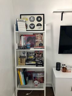 a white book shelf filled with books next to a flat screen tv