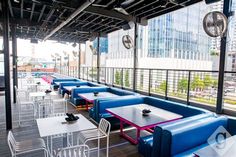 tables and chairs are lined up on the roof deck at an outdoor restaurant with large windows