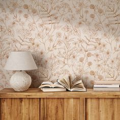 an open book sitting on top of a wooden table next to a lamp and vase