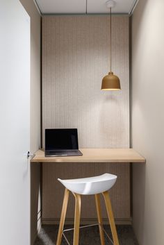 a laptop computer sitting on top of a wooden desk next to a white chair and lamp