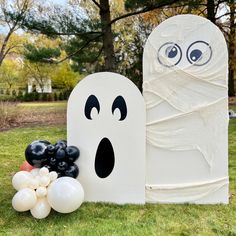 two halloween decorations are on the grass in front of a white ghost and black grapes